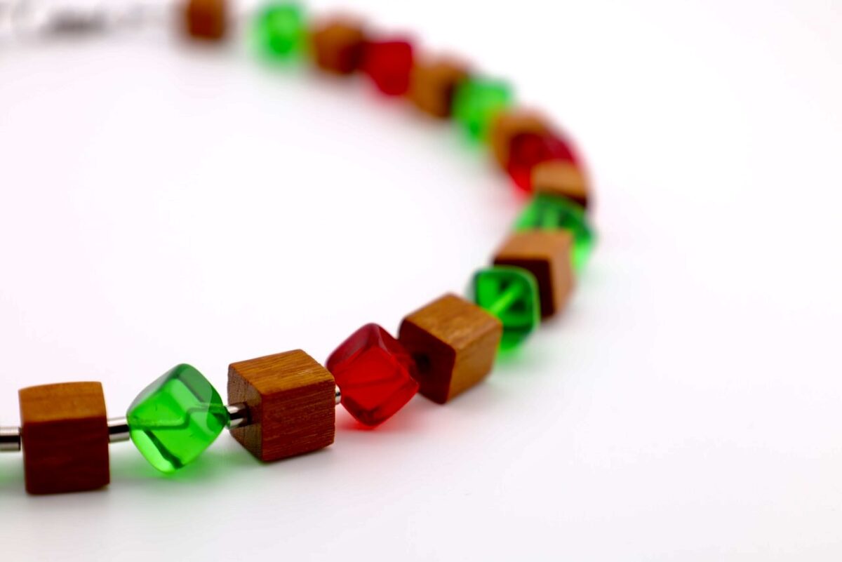 Handgefertigte Würfelkette aus Pau Rosa Holz und Glasperlen in Rot und Grün. Natürliches Edelholz trifft auf farbige Akzente – einzigartiger Schmuck von HotzenArt.